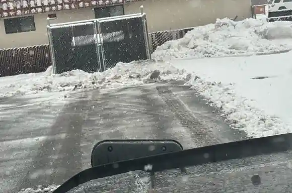 A snowy lot being plowed, seen over the plow blade