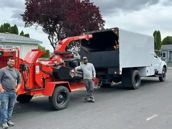 Two of the Big R crew beside their red chipper and white chip truck